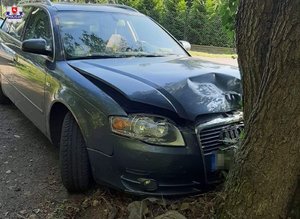 stojący przy drzewie uszkodzony samochód marki Audi