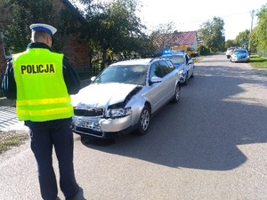 policjant, uszkodzony samochód audi i policyjne radiowozy