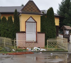uszkodzona kapliczka i leżąca na jezdni rozbita figura Matki Boskiej