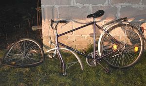 uszkodzony rower stojący przy ścianie budynku
