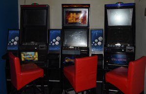 trzy automaty do gier hazardowych i stojące przy nich fotele