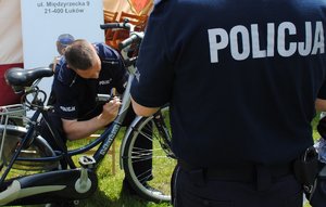 policjant nanosi urządzeniem oznaczenia na ramie roweru